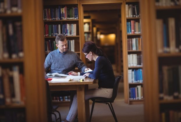 Mature students working together in college library